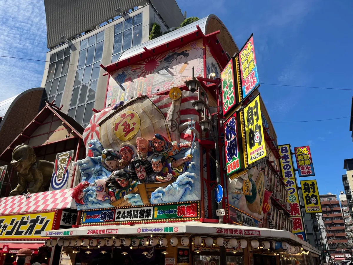 串かつ店や射的の大きな看板が並ぶ、にぎやかな新世界の街並み