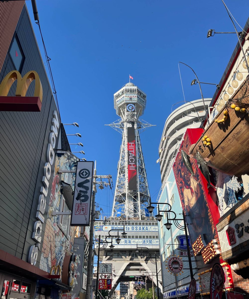 青空にそびえる通天閣と、にぎやかな新世界の通り